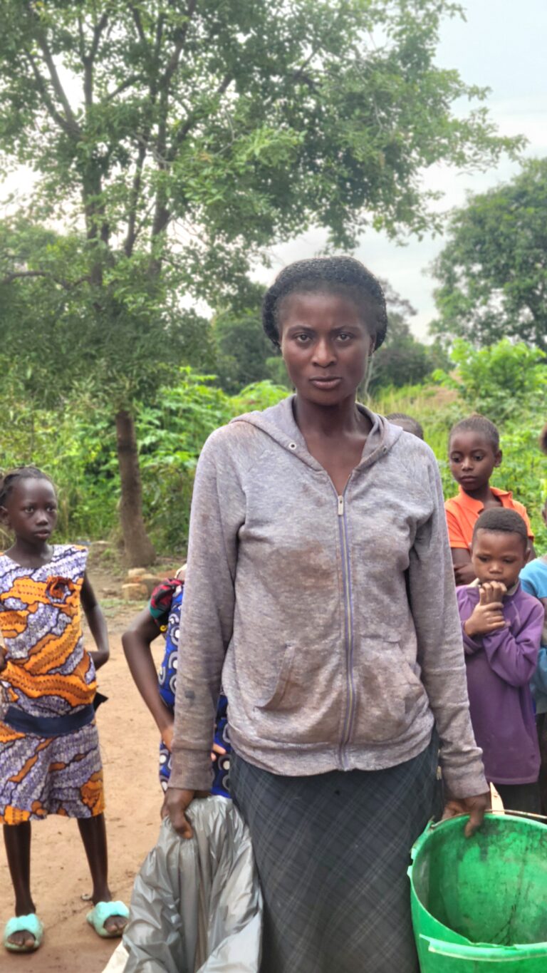 A young woman standing with children in a rural community in Congo