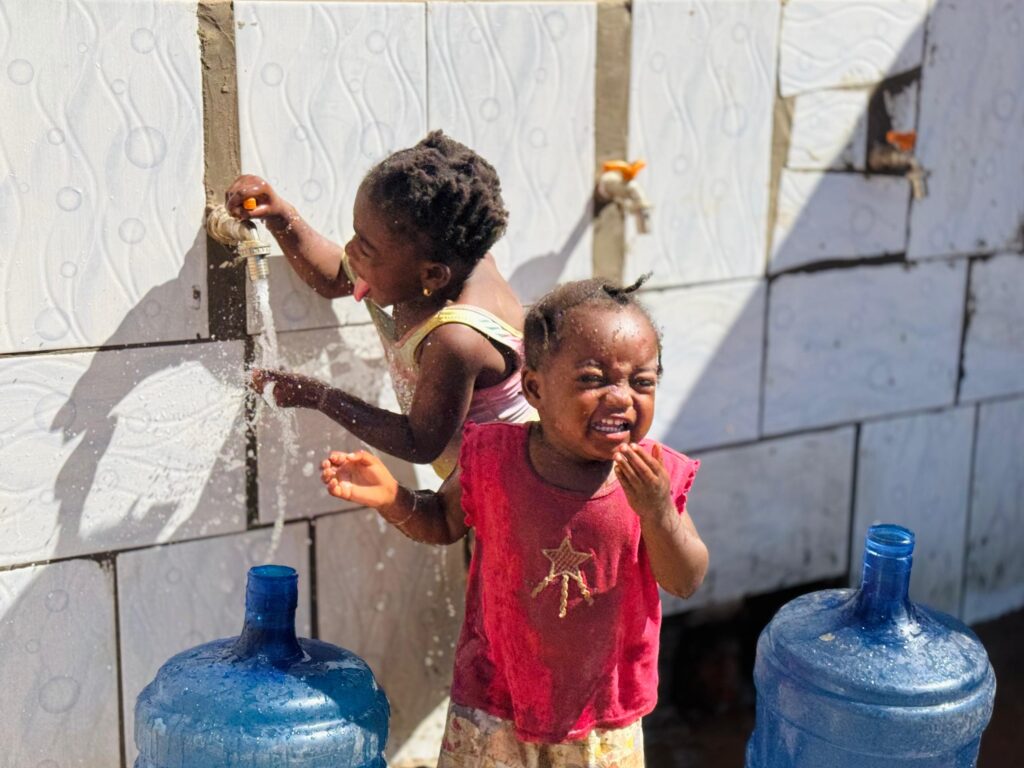 A child drinking from a tap fed by a Hope G.C.L.M. community water well in the Democratic Republic of Congo